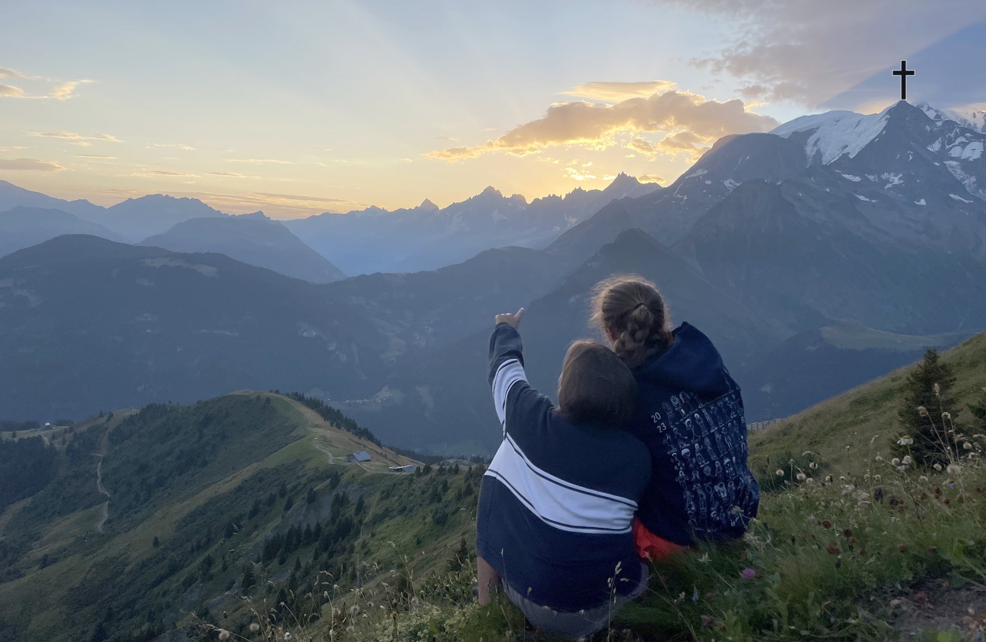Deux jeunes au sommet, lever de soleil sur les Alpes et croix de sommet